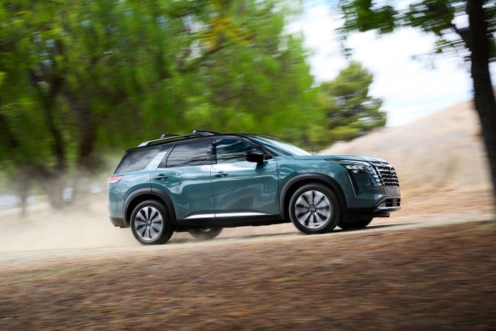 Right profile view of the 2026 Nissan Pathfinder driving on a path with trees behind.