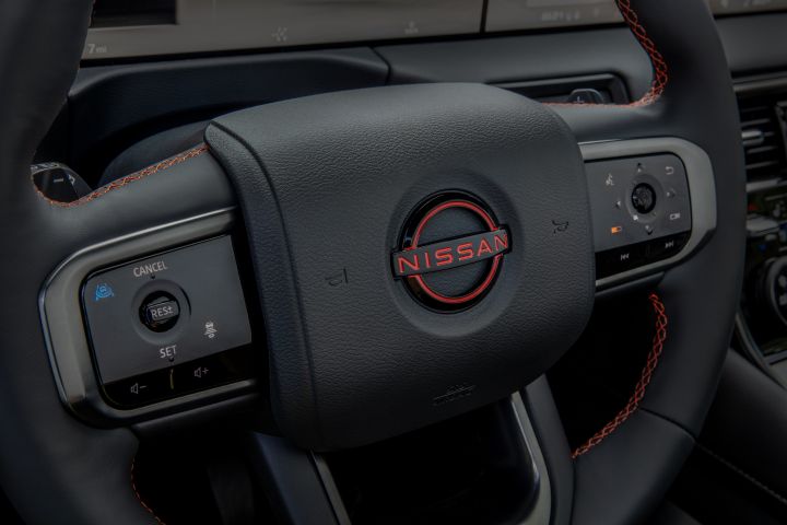 Close up of the black and red stitched steering wheel in the 2025 Nissan Armada, the Nissan logo in the center is red.