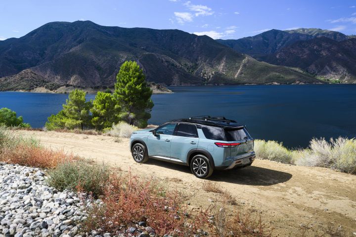 The 2026 Nissan Pathfinder parked on a dirt path overlooking mountains and a body of water.