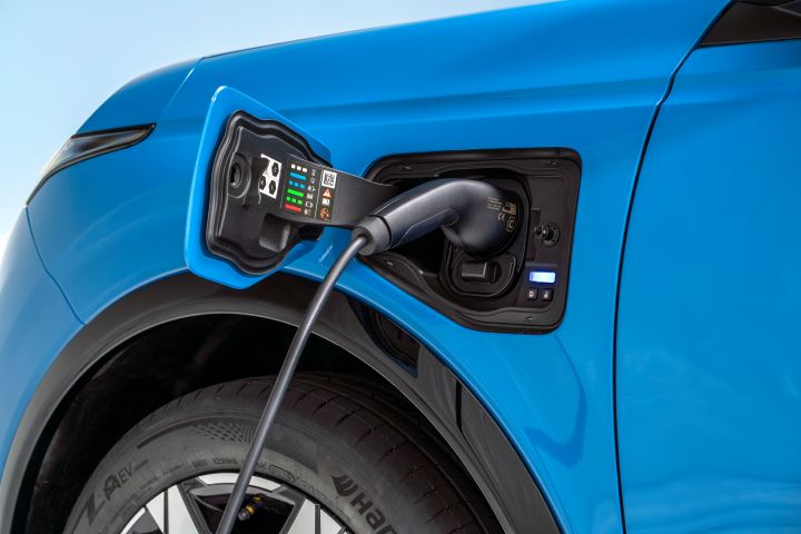 detailed shot of open electric charging port with a charger plugged in on left side above the wheels