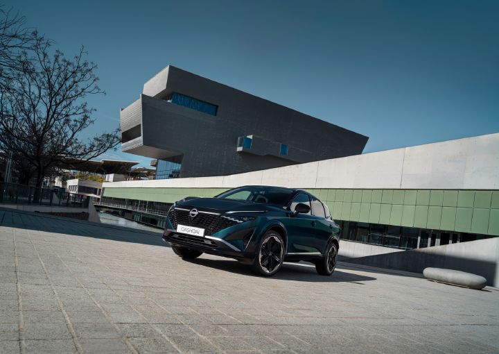 Nissan Qashqai parked in front of a modern architectural building, shown from a front three-quarter angle