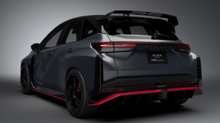 A silver and black two-tone sports car, the Aura Nismo RS Concept, photographed in a studio from a rear-right angled view. The vehicle is stationary, featuring a black plate with white text reading 'AURA NISMO RS CONCEPT' at the center of the rear, along with a red accent line and the NISMO logo on the lower bumper. A large rear wing is mounted, and the side displays a light gray 'RS.' The background is a simple gray gradient, highlighting the car's sporty design."