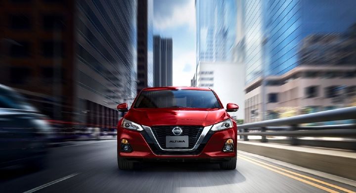 Una representación artística de un Nissan Altima rojo con la mitad izquierda de la noche y la derecha mitad del día.