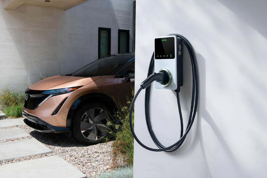 Image of a domestic AC-charger next to a gold 2025 Nissan ARIYA SUV parked at a home