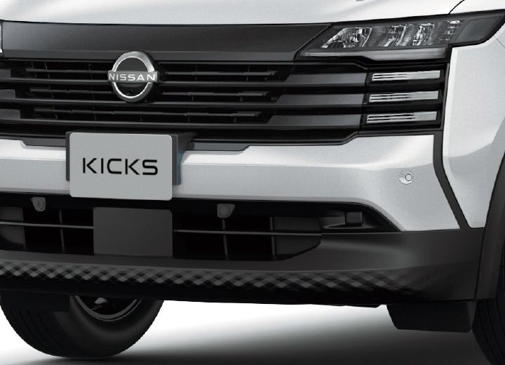 Close-up of the front face of a white Nissan Kicks. The grille and bumper design are emphasized head-on.