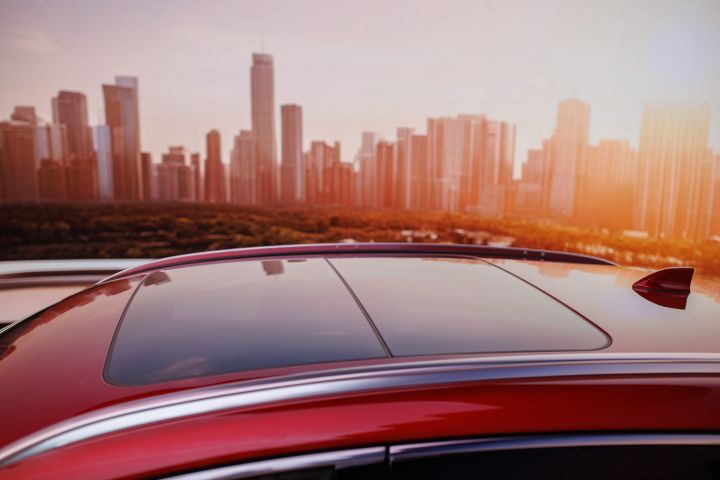 The red roof and sunroof on the silver 2025 Nissan Kicks with a cityscape in the background.