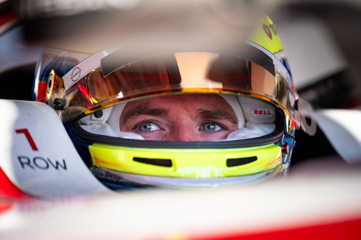 Oliver Rowland sitzt mit aufgesetztem Helm und hochgeklapptem Visier im Auto mit der Startnummer 1 in der Teamgarage.