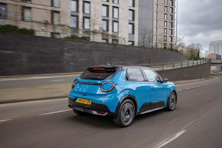 Rear view of a Blue Nissan MICRA driving along a road