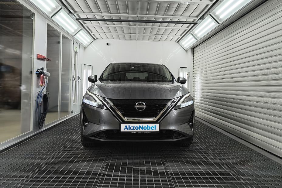 Nissan Qashqai przodem w komorze lakierniczej, z logo Akzo Nobel na tablicy rejestracyjnej