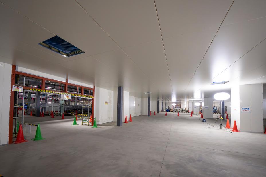 Blick auf die Baustelle im Werk Yokohame für die Pilotanlage für Feststoffbatterien, von einem Teil mit hellen Decken, Wänden und Böden blickt man in die Fabrikanlage