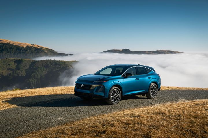 Front left 3/4 angle of a blue 2025 Nissan Murano, it is parked on land with high elevation, a cloud is seen swirling behind.