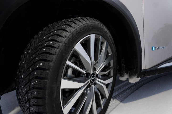 Detailansicht Leichtmetallräder und Reifen des Nissan X‑Trail auf Schnee schräg von vorne