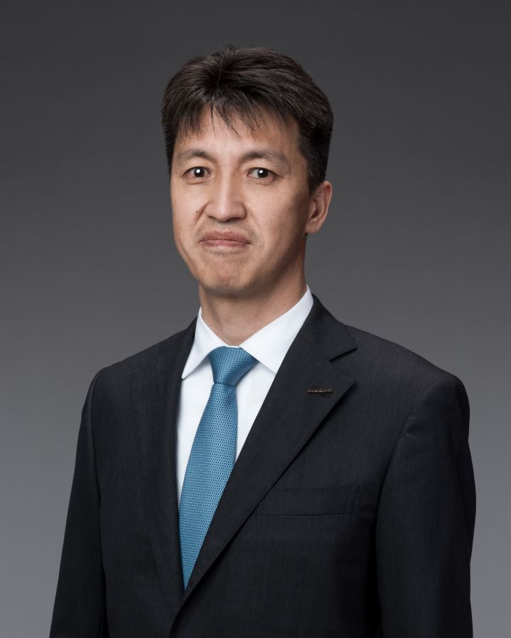 さかね まなぶ_肖像写真（スーツにネクタイ、NISSAN社章）