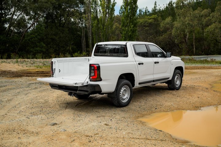 2026 Nissan Navara SL dual cab ute finished in Alpine White shown from the rear-left angle with the tailgate open, highlighting the tray opening and utility-focused rear design.