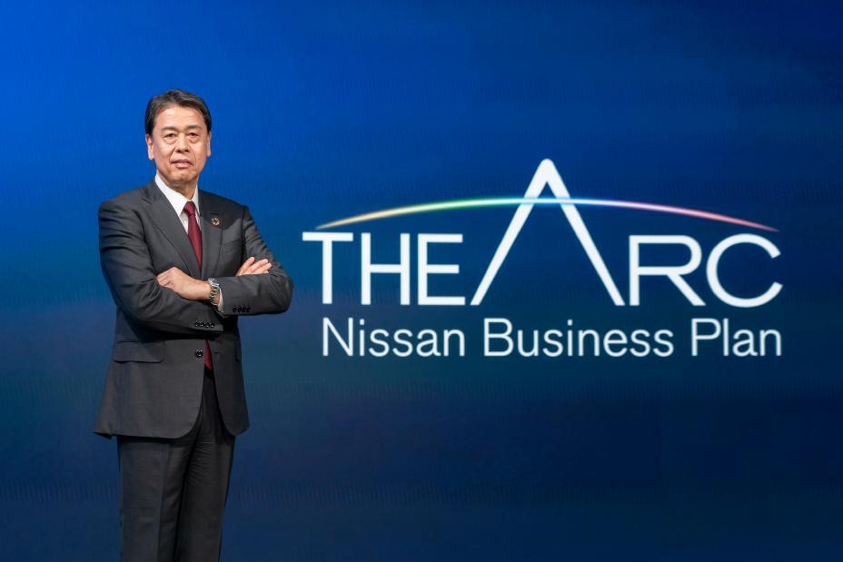 Makoto Uchida pose à côté du logo du nouveau plan à moyen terme de Nissan