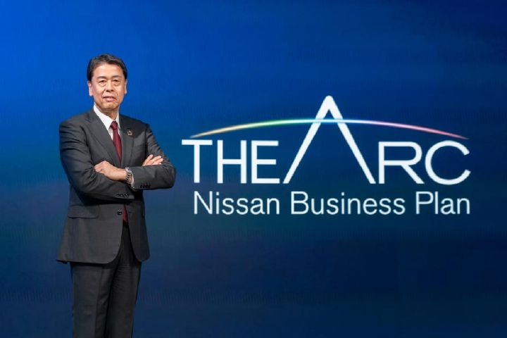 Makoto Uchida pose à côté du logo du nouveau plan à moyen terme de Nissan