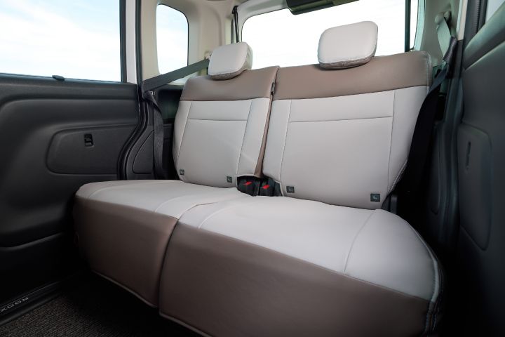 Rear seats of the new Nissan Roox kei car. The two-tone greige and brown upholstery includes two headrests and visible seat belts, creating a cohesive and calm interior design.