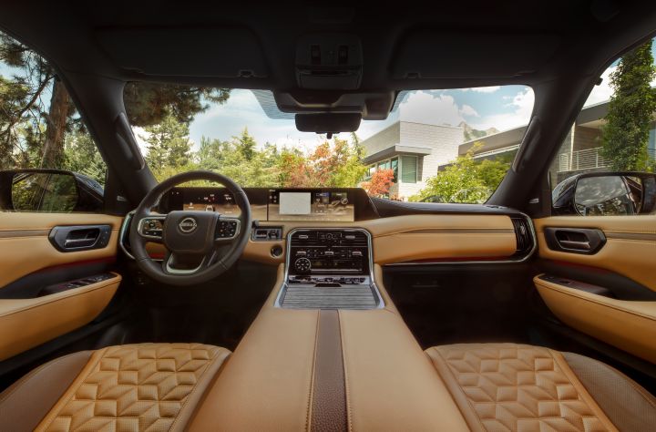 The tan and black interior, dashboard, and center console viewed from the rear passenger seats.