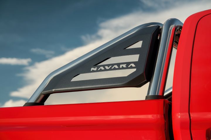 Close-up of the sports bar on a 2026 Nissan Navara ST-X in Outback Red, showing the chrome uprights and black insert with NAVARA cut-out against a blue sky.