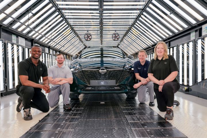 Neben einem neuen Nissan Qashqai in Dunkelgrün knien vier Menschen auf der Produktionslinie des Nissan Werks in Sunderland