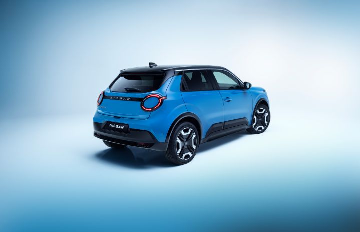 rear 3/4 view of Micra in blue gear body color with signature lit headlamps, wheels, black roof, Nissan nameplates and passenger front/rear doors