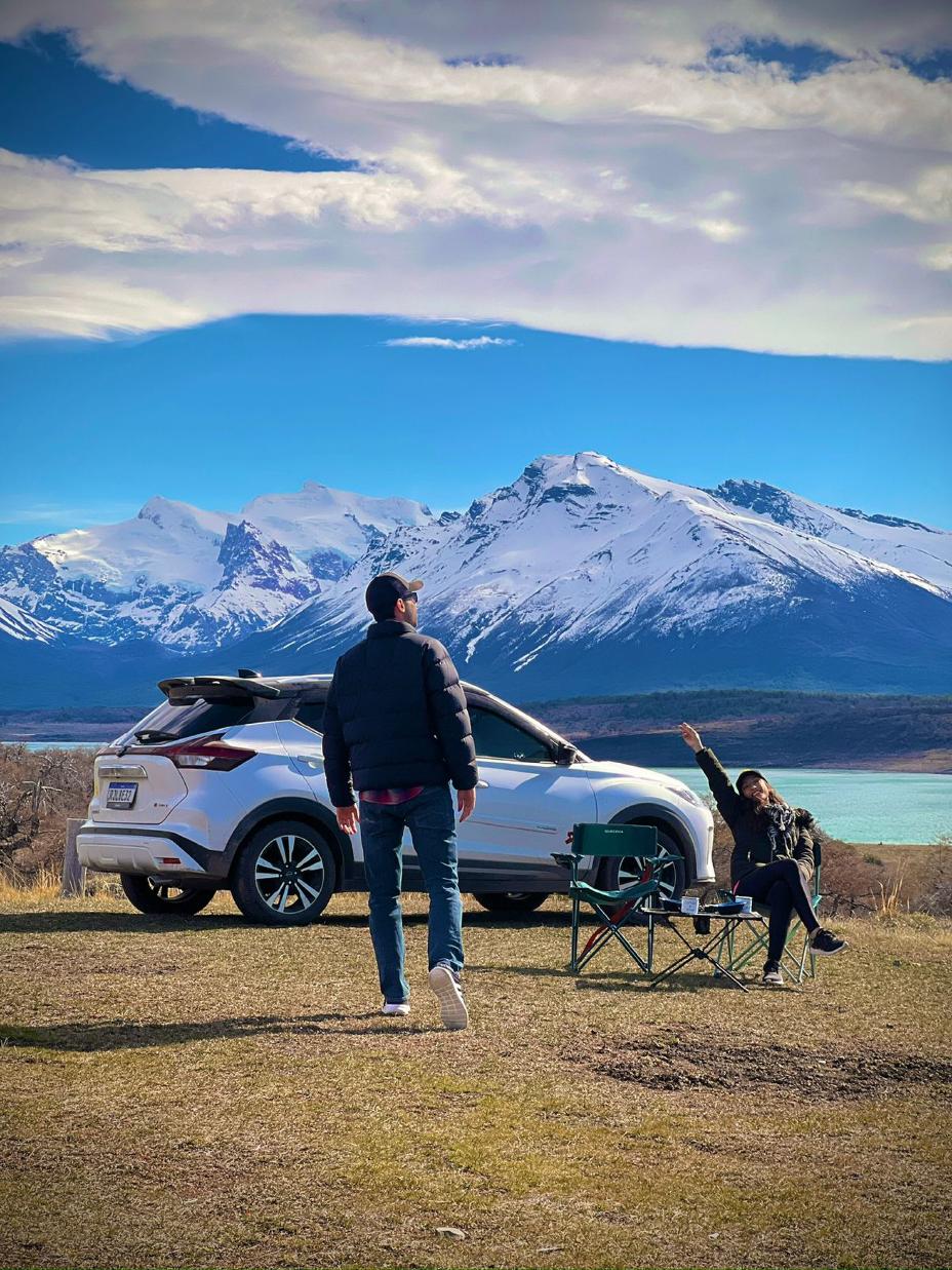 Um homem e uma mulher com seus Nissan Kicks em frente a uma montanha