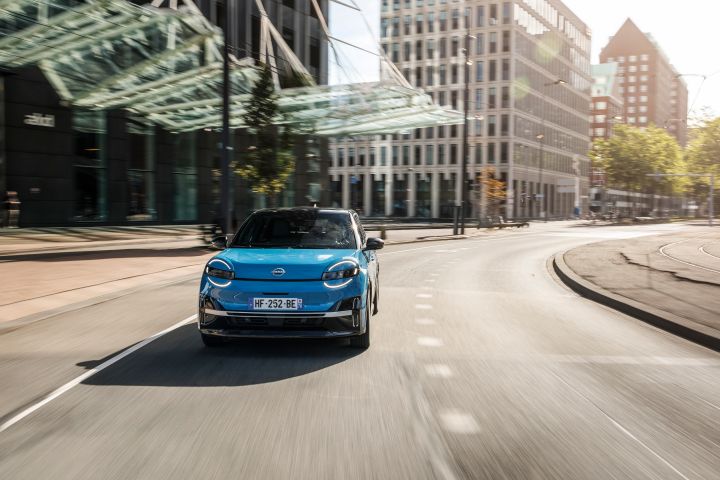 Frontale Fahraufnahme eines blauen Nissan Micra auf einer breiten, hellen Straße