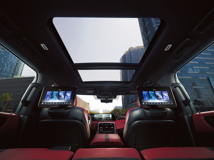 The interior of the Patrol viewed from the rear seats. Dual monitors are installed in the back, and a panoramic sunroof reveals a city skyline.