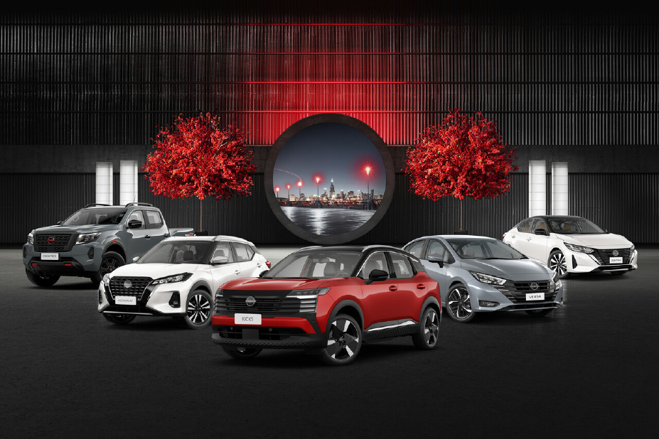 Imagem mostra a linha atual de veículos da Nissan, composta por diferentes modelos como SUVs e sedãs, dispostos lado a lado em ambiente iluminado com fundo urbano e elementos decorativos em vermelho