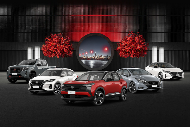 Imagem mostra a linha atual de veículos da Nissan, composta por diferentes modelos como SUVs e sedãs, dispostos lado a lado em ambiente iluminado com fundo urbano e elementos decorativos em vermelho