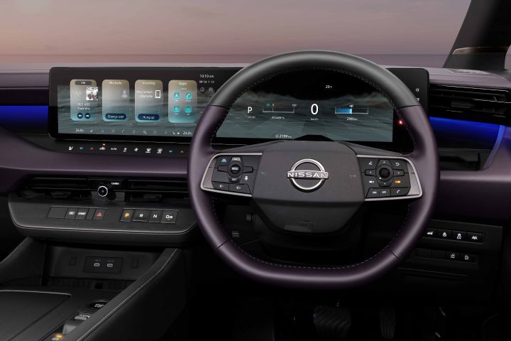 The driver’s area of a Fuji-dawn-colored Elgrand. The steering wheel and multiple digital displays are shown, displaying navigation and vehicle information.