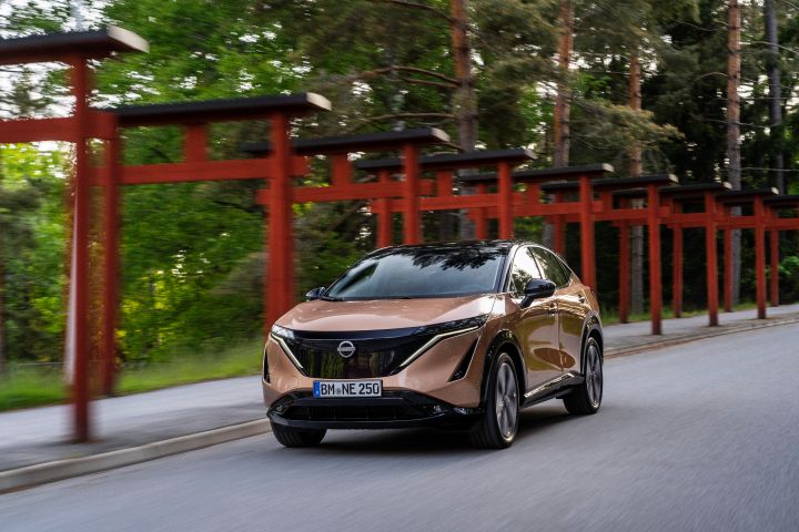 Nissan Ariya roulant sur une route bordée d’éléments architecturaux d’inspiration japonaise »