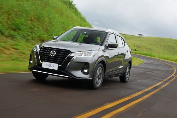 Nissan Kicks na cor cinza em fundo branco, estacionado de três quartos de frente.
