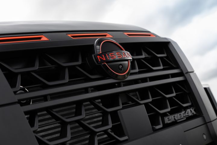 2026 Nissan Navara PRO-4X finished in Boulder Grey showing a low-angle grille close-up with Nissan badge, red accents and PRO-4X branding.