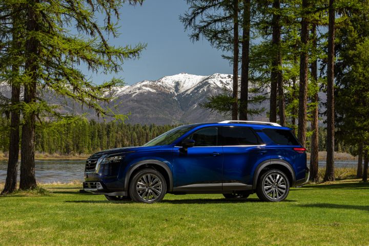 A blue 2022 Nissan Pathfinder parked on grass in front of a lake