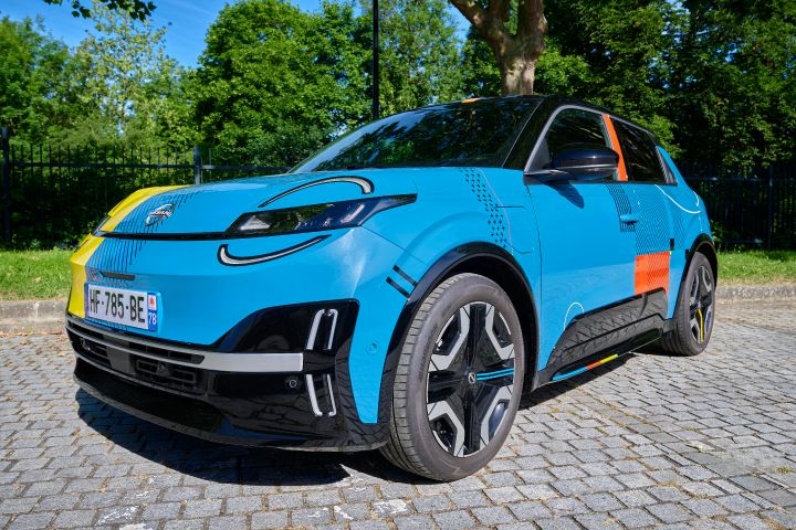 Das blaue Nissan Micra Signature Edition Gewinnerfahrzeug mit schwarzem Dach, auffälligen roten, gelben und schwarzen grafischen Akzenten sowie sportlichen Felgen, ausgestellt in einem roten Kreis.