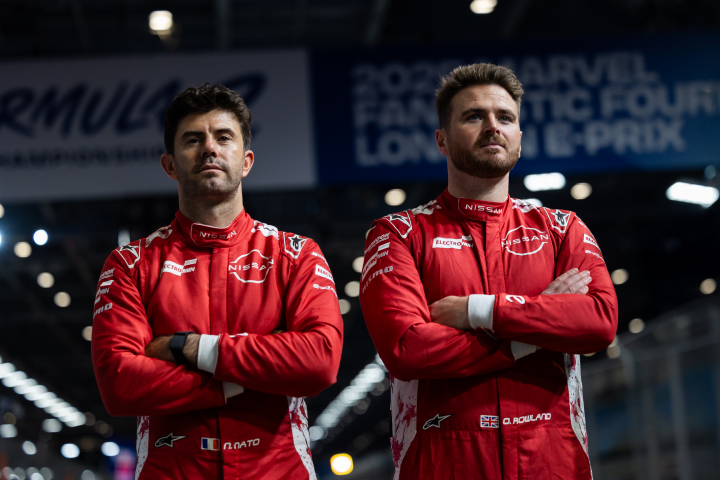 Norman Nato (po lewej) i Oliver Rowland (po prawej) w czerwonych kombinezonach wyścigowych Nissan Formula E Team z założonymi rękami.