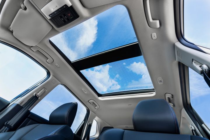 Das neue Panorama-Schiebedach im Innenraum des 2026 Nissan X‑Trail gibt den Blick auf einen blauen Himmel mit vereinzelten Wolken frei. Zur Ausstattung gehören schwarze Ledersitze, eine helle Decke und Bedienelemente für das Schiebedach im vorderen Bereich.