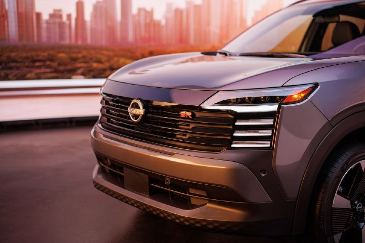 Nueva Kicks bitono gris con rojo, muestra el frente de cerca con la parrilla cromada y las luces delanteras, integradas en la parte superior de la parrilla y nuestro logo Nissan al centro.