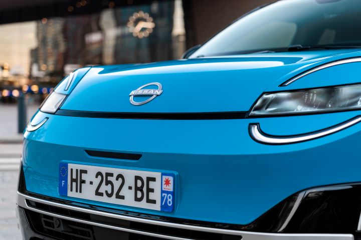 Detailaufnahme der Frontpartie eines blauen Nissan Micra mit Fokus auf das Markenlogo