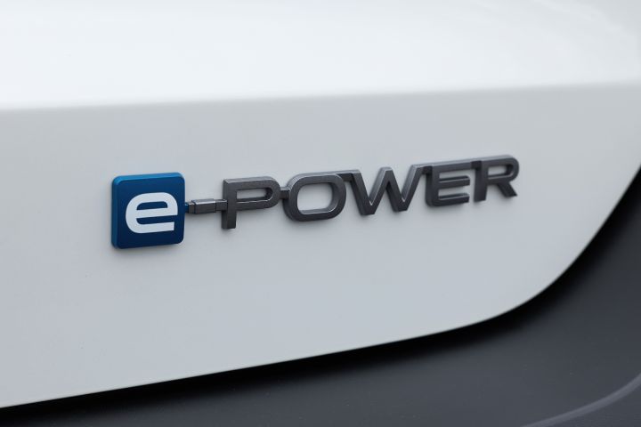 白系キックスの「e‑POWER」エンブレムのクローズアップ。ロゴが水平に配置され、ボディの滑らかな塗装面が強調されている。