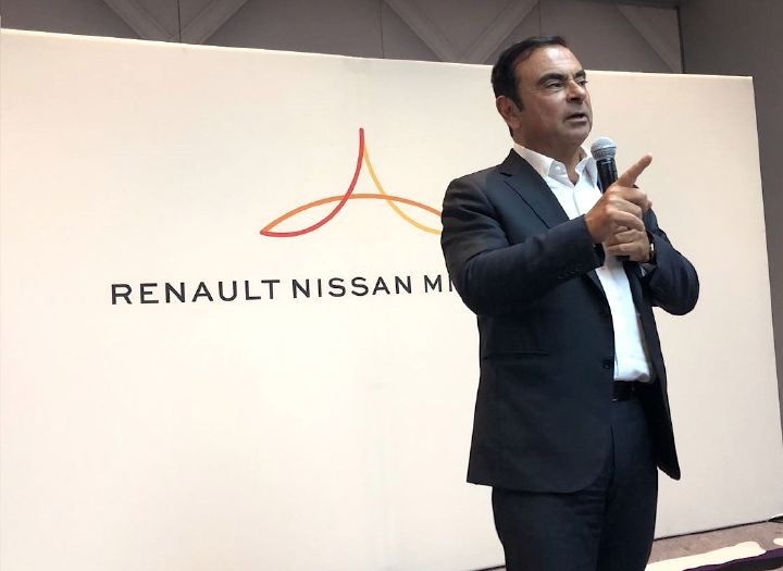 A man giving a speech at an event for Renault Nissan Mitsubishi.