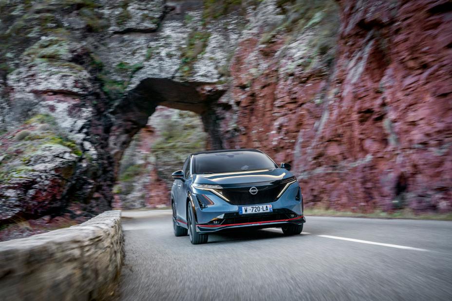 Front view dynamic shot of Ariya NISMO passing through a natural mountain tunnel.