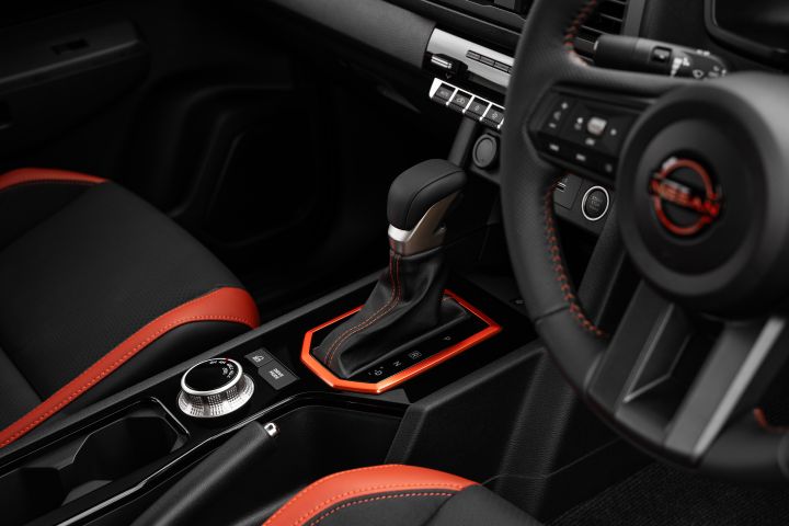 2026 Nissan Navara PRO-4X finished in Boulder Grey detailing the driver area with automatic shifter, rotary selector, cupholders and red-stitched console trim.