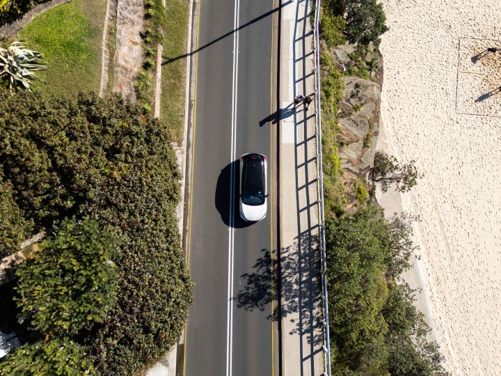 Nissan Leaf driving down a road next to a beach