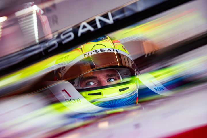 Oliver Rowland sitzt mit aufgesetztem gelbem Helm und hochgeklapptem Visier im Auto mit der Startnummer 1 in der Teamgarage.