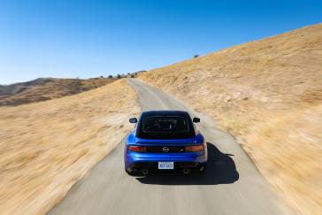 Rear view of a blue 2023 Nissan Z driving on the road.