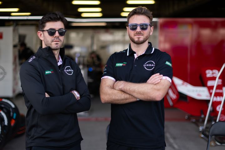 Norman Nato und Oliver Rowland stehen mit verschränkten Armen vor der Nissan Box, sie tragen Teamkleidung und Sonnenbrillen.