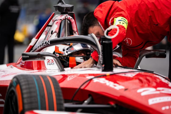 Norman Nato sitzt in seinem Nissan Formula E Rennwagen, ein Teamkollege beugt sich über ihn und erledigt etwas am Auto