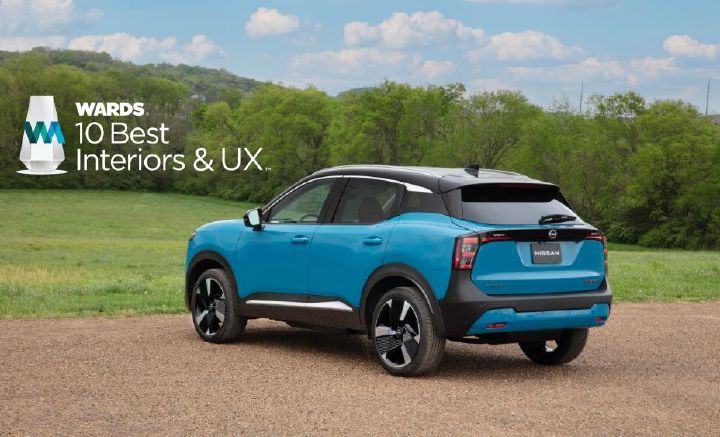 Left rear 3/4 view of a blue 2025 Nissan Kicks parked on gravel near grass. An award logo is in the top left.
